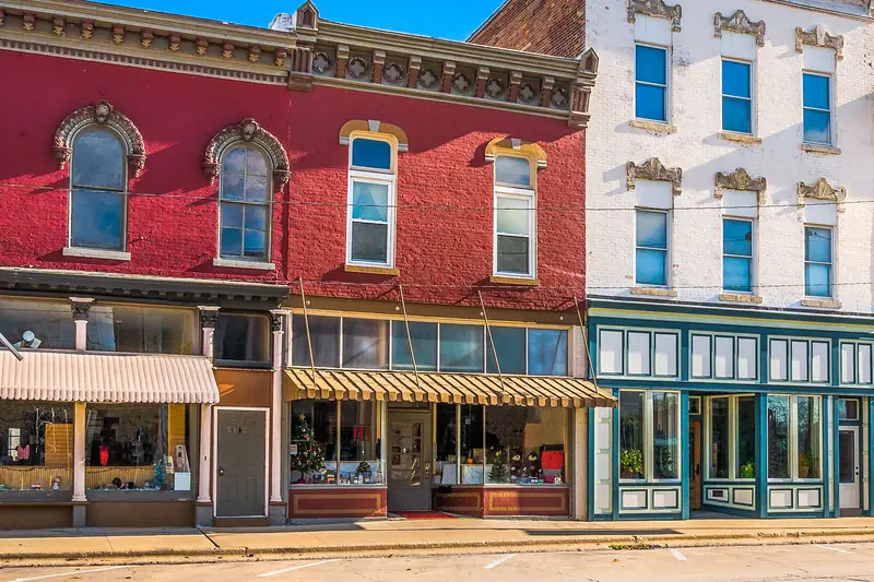 A row of brick storefronts with striped awnings on a small-town main street.